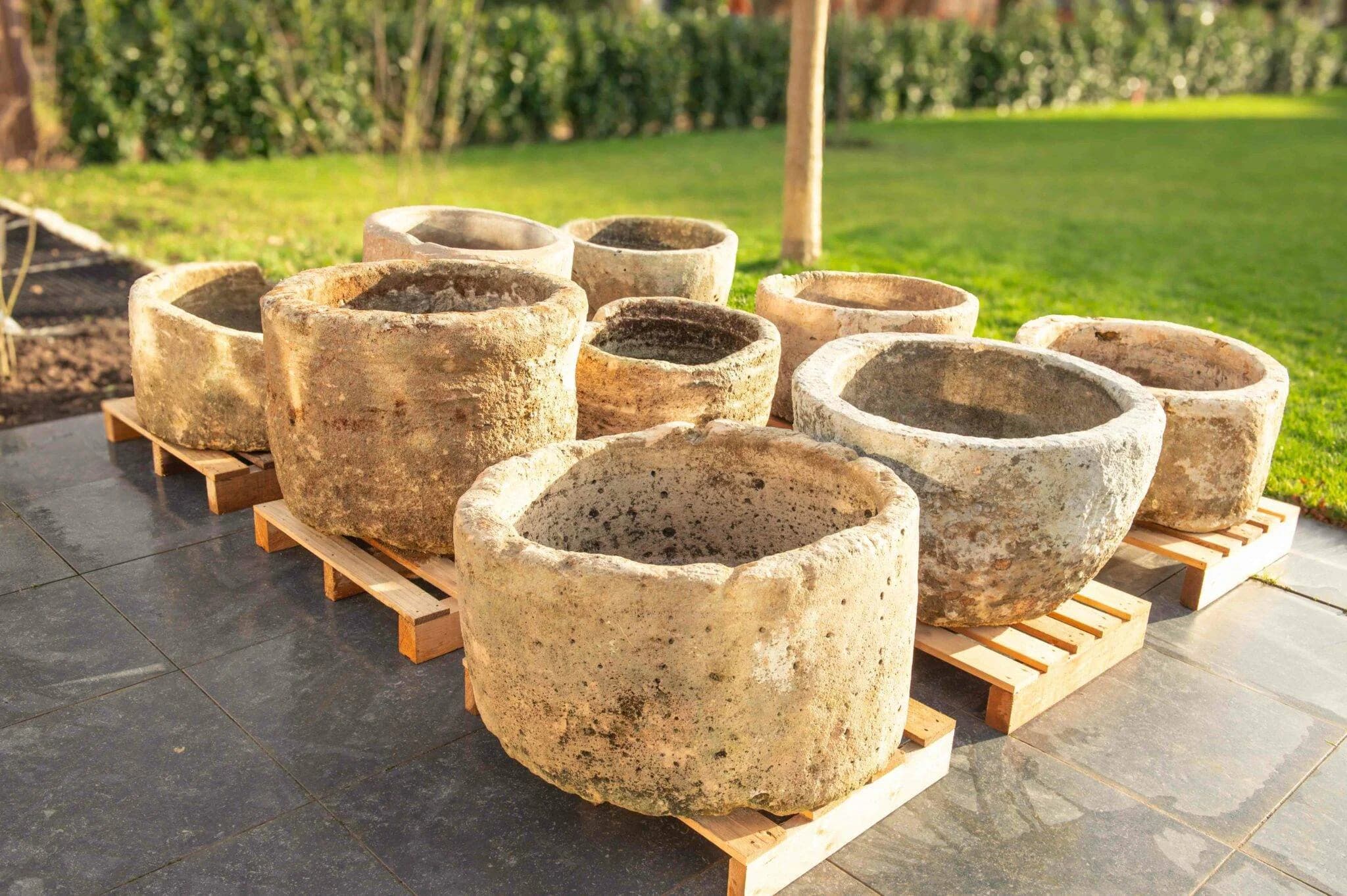 Natuurstenen potten op pallets bij een tuinproject in avondlicht